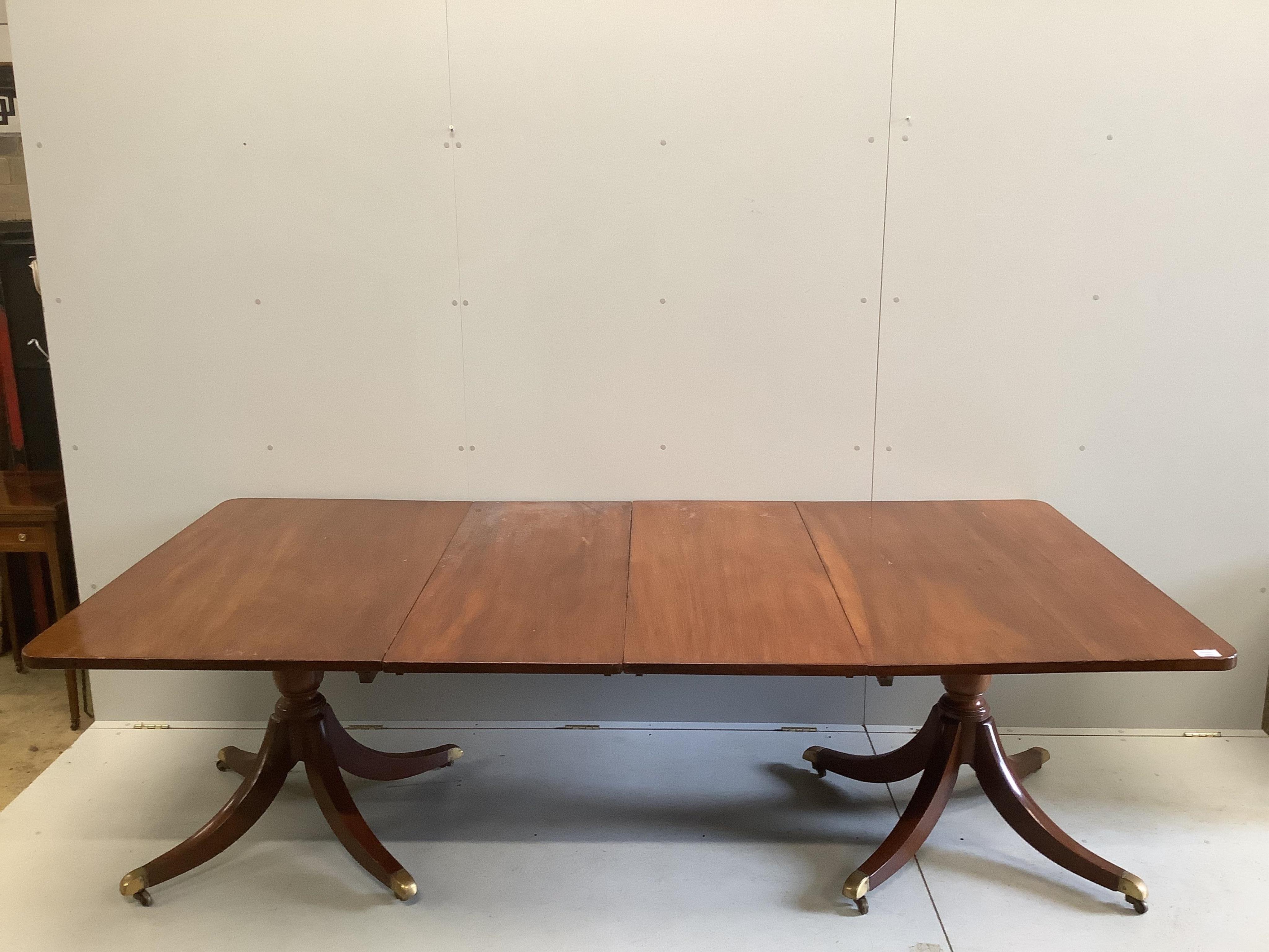 A Regency mahogany twin pillar extending dining table, width approximately 240cm extended, two spare leaves, depth 120cm, height 72cm. Condition - fair